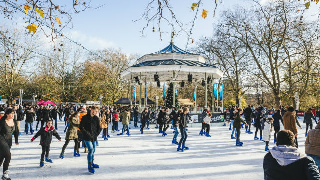 Schlittschuhlaufen im Hyde Park beim Winter Wonderland an einem sonnigen Wintertag um die Tribüne 