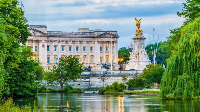 Buckingham Palace behind a lake on a cloudy day in London.