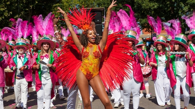 A woman with feathered wings and a sequined costume at a parade during Notting Hill Carnival in London.