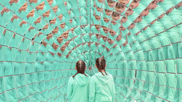 Two children stand in a room of infinity mirrors at the Science Museum in London.