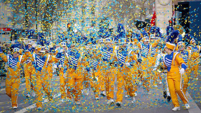 A marching band dressed in yellow and blue walk through confetti at London's New Year's Day Parade.