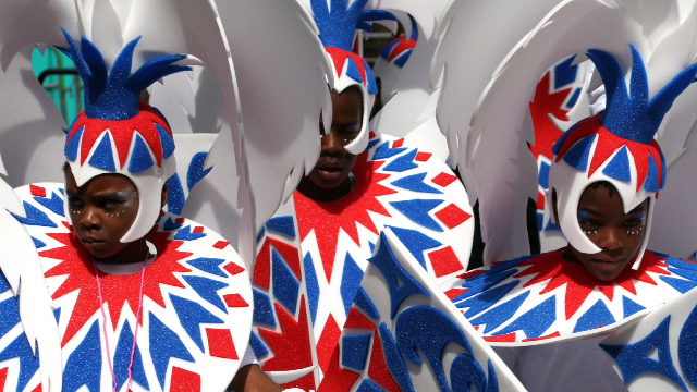 Three children dressed in white, red and blue outfits performing at London's Notting Hill Carnival.