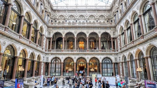 The interior of the Foreign, Commonwealth and Development Office with people gathering in the main atrium, below arches and columns.