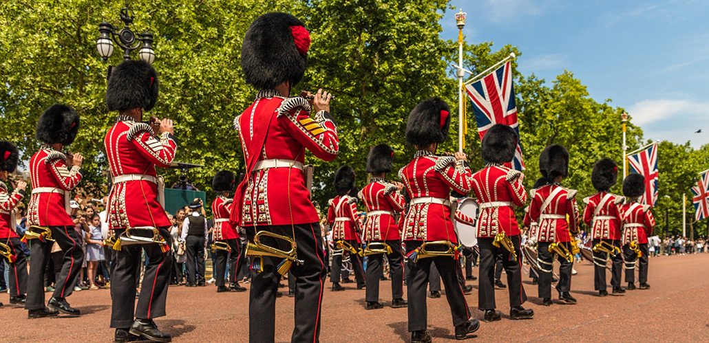 Les gardes, vêtus de tuniques rouges avec des chapeaux noirs en peau d’ours, jouent des instruments alors qu’ils marchent le long de l'avenue The Mall en direction de Buckingham Palace.