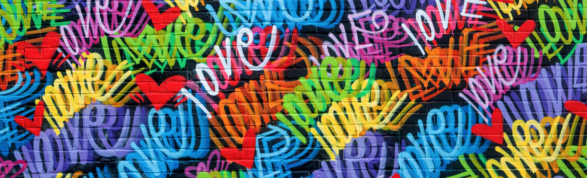 Close up of street art in Shoreditch featuring spray painted hearts and the word love in different colours. 