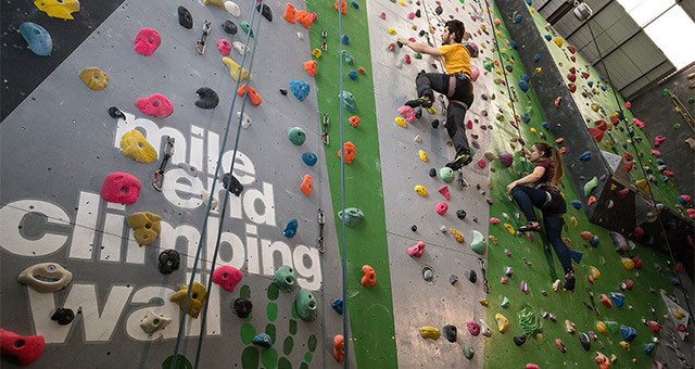 A man and woman climbing Mile End Climbing wall with ropes