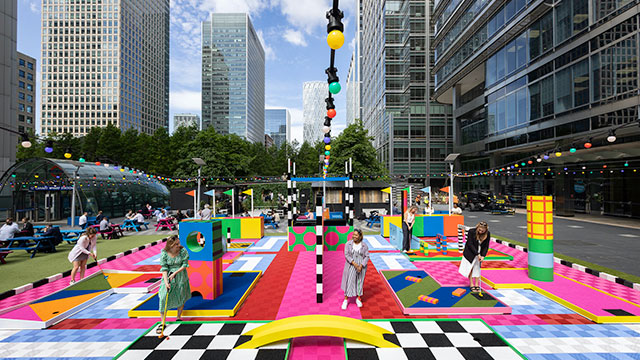 A group of women putt their way around a colourful mini-golf course at Canary Wharf on a sunny day