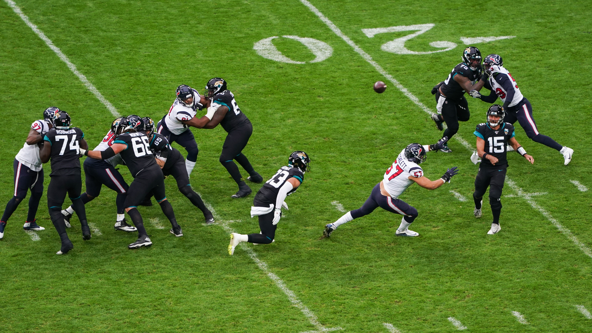 Action shot of 12 NFL players against the bright green pitch and 20 line during Houston Texans at Jacksonville Jaguars game. 