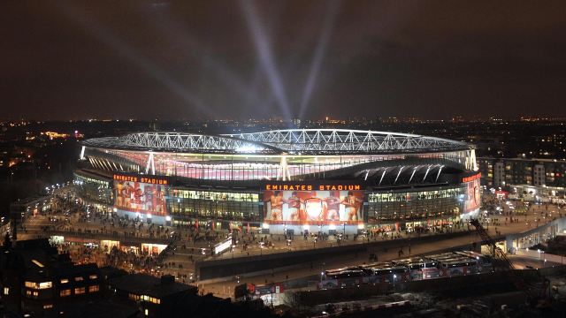 Aerial view of London's lit-up Emirates Stadium at night.