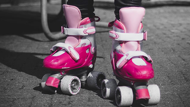 A child wearing pink and white roller skates on a sunny day