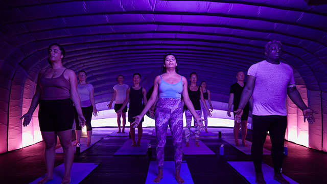 A hotpod yoga class in a dark pod with pink lights