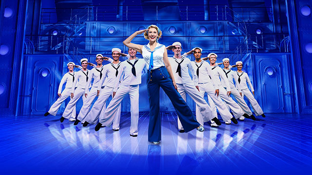 The Anything Goes cast dancing in sailor outfits on stage in front of a blue background