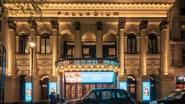 London's Palladium Theatre entrance at night with black cab in the foreground.