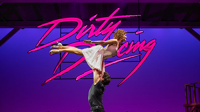 Johnny wie er Baby am Ende ihres Tanzes vor einem rosa Dirty-Dancing-Logo hochhebt