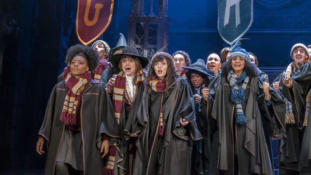 Un groupe d'étudiants de Poudlard portent les uniformes des maisons Griffondor, Serdaigle et Poufsouffle sur la scène de théatre de Harry Potter et l'Enfant Maudit.