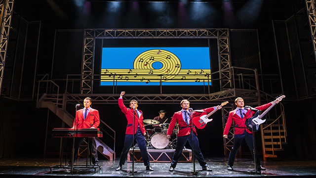 Les Jersey Boys, quatre hommes tous vêtus de vestes rouges, jouent une de leurs chansons sur la scène du Trafalgar Theatre.