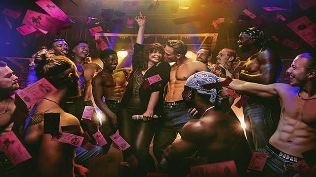 A women is surrounded by men from the cast of Magic Mike throwing pink notes in the air.
