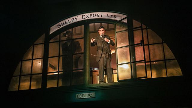 Der Schauspieler der Tommy Shelby spielt, steht während einer Rede an einem Fenster von einem  Warenhaus. 