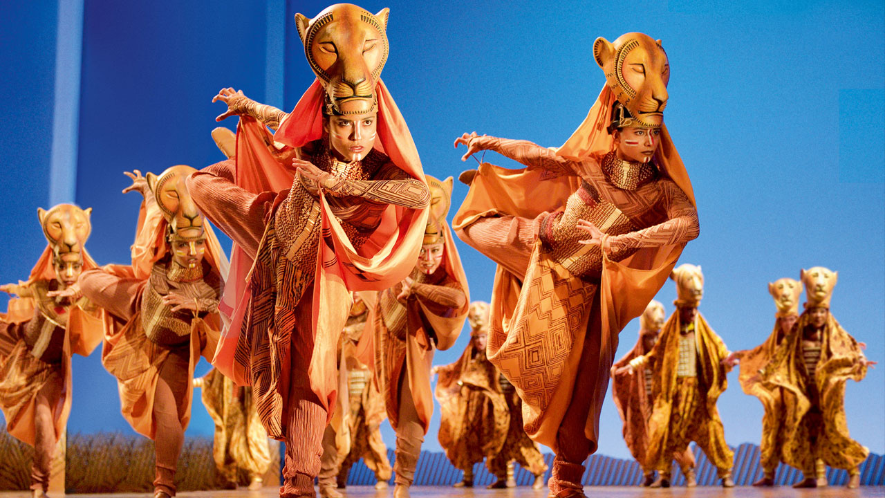 Four dancers leap across the stage in lion costumes in The Lion King.