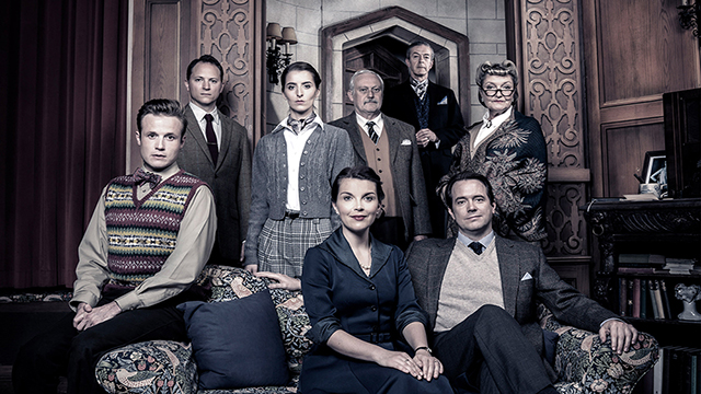 The cast of The Mousetrap sits in the living room of a country side house and look mysteriously at the camera.