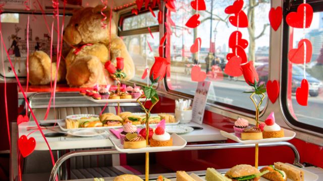 An afternoon tea bus tour booth table covered in valentines sweet treats and valentines decorations.