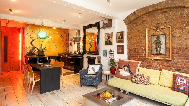 Airbnb living room featuring colourful furniture, red-brick walls and wooden floorings.