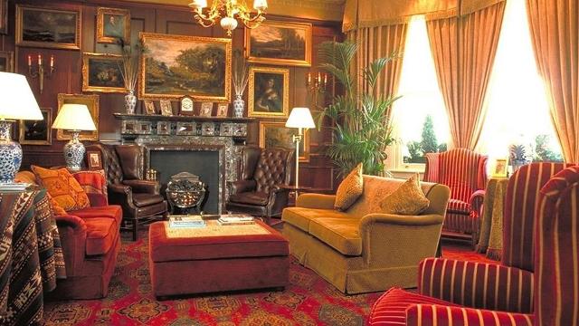 The Victorian lobby area at The Exhibitionist Hotel, featuring red sofas, yellow curtains and art on the wall.
