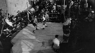 A boxing contest aboard HMS Queen Elizabeth (1913). The boxing ring has been set up on the port side of the shelter deck just forward of the mainmast. The officiating officers are Chaplain the Rev H G Rorison MA and Commander F A Beasley. © National Maritime Museum, London