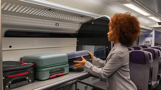 A woman stowing a suitcase. Credit: Laurence Lennard. Image courtesy of Heathrow Airport. A woman stowing a suitcase. Credit: Laurence Lennard. Image courtesy of Heathrow Airport.