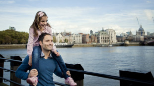 A father and daughter walk along the Thames in London