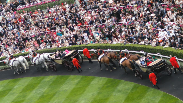 Horses pulling a vehicle in which the Queen is sitting.